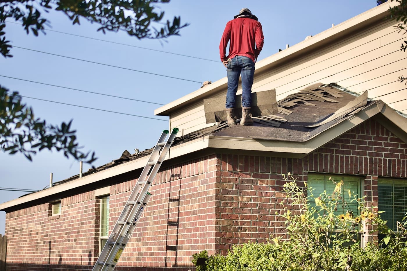 A roofer replacing shingles on a residential roof