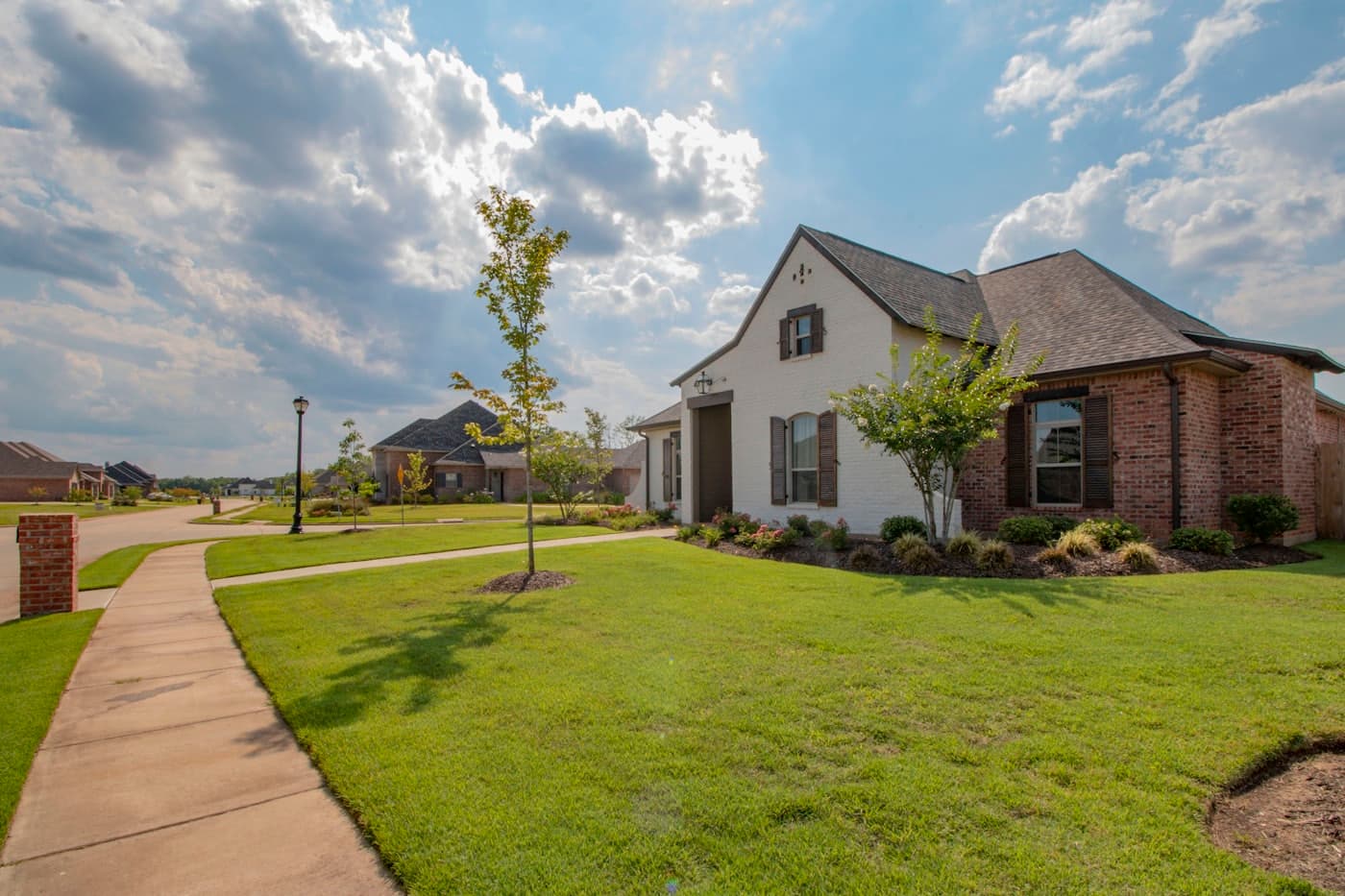 A bright suburban home with a new shingle roof under a blue sky