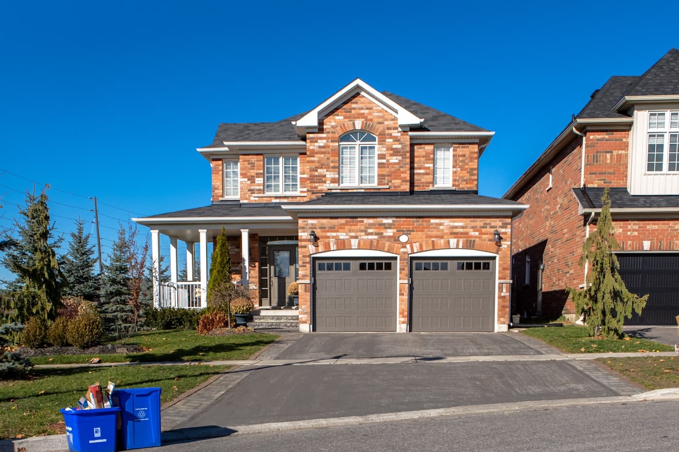 A brick two-story home with a new architectural shingle roof under a clear blue sky
