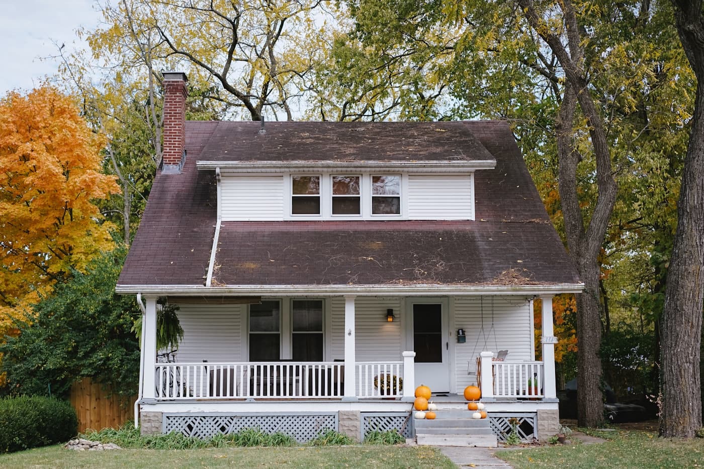 A house with an aged, weathered dark shingle roof in need of repair and restoration
