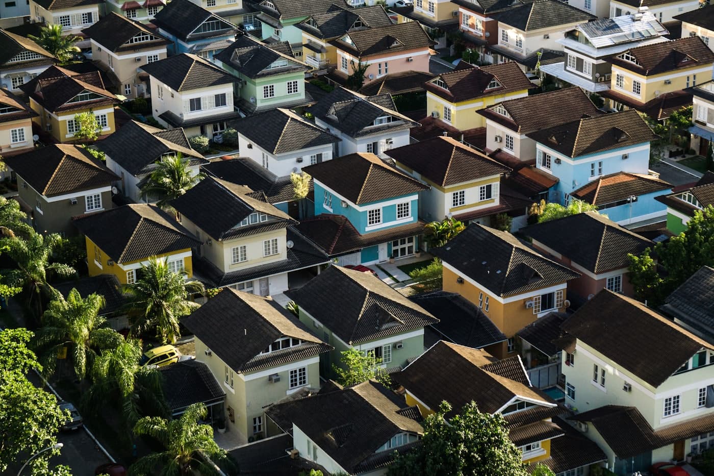 An aerial view across a neighborhood of pitched residential rooftops