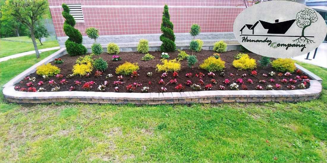 Freshly laid dark mulch beds curving along a fence line behind a green lawn