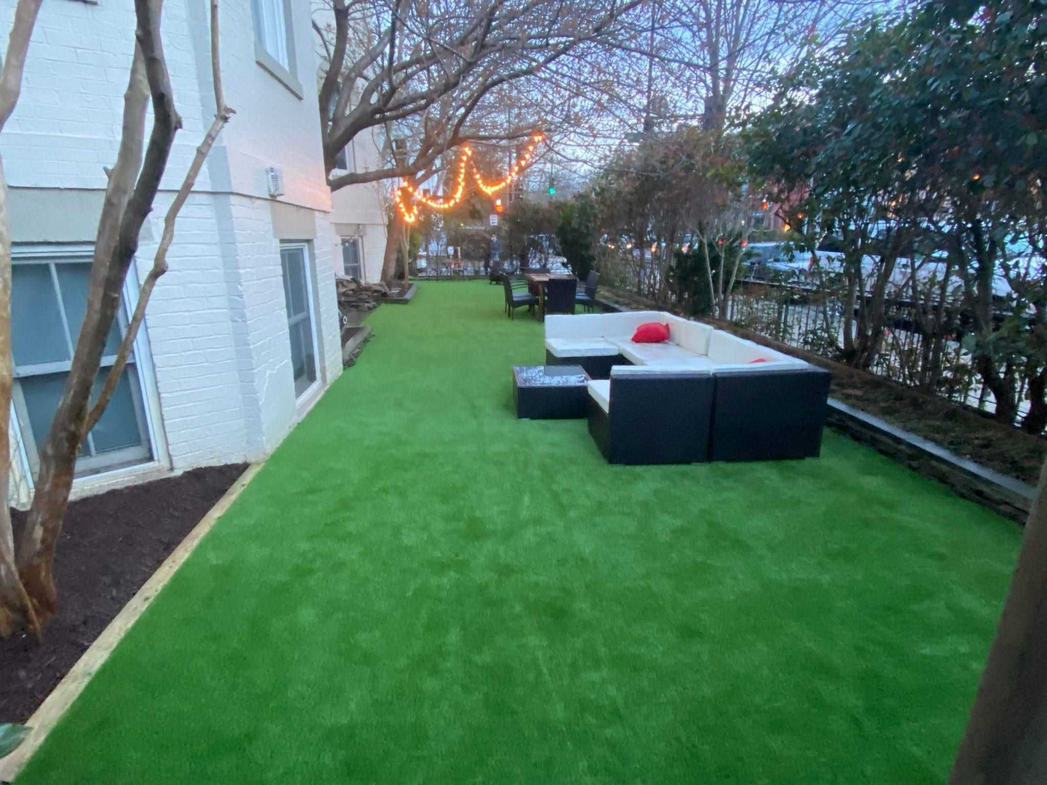 Lounge seating and string lighting on the finished lawn of a Washington DC rowhouse garden